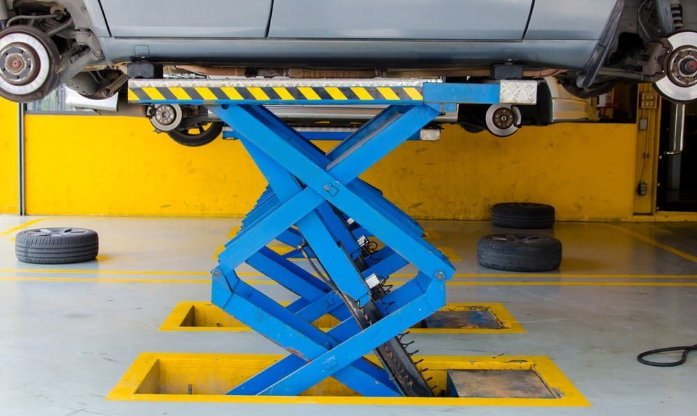 A Car Is Sitting On Top Of A Scissor Lift In A Garage — Aspire Diesel In Gracemere, QLD