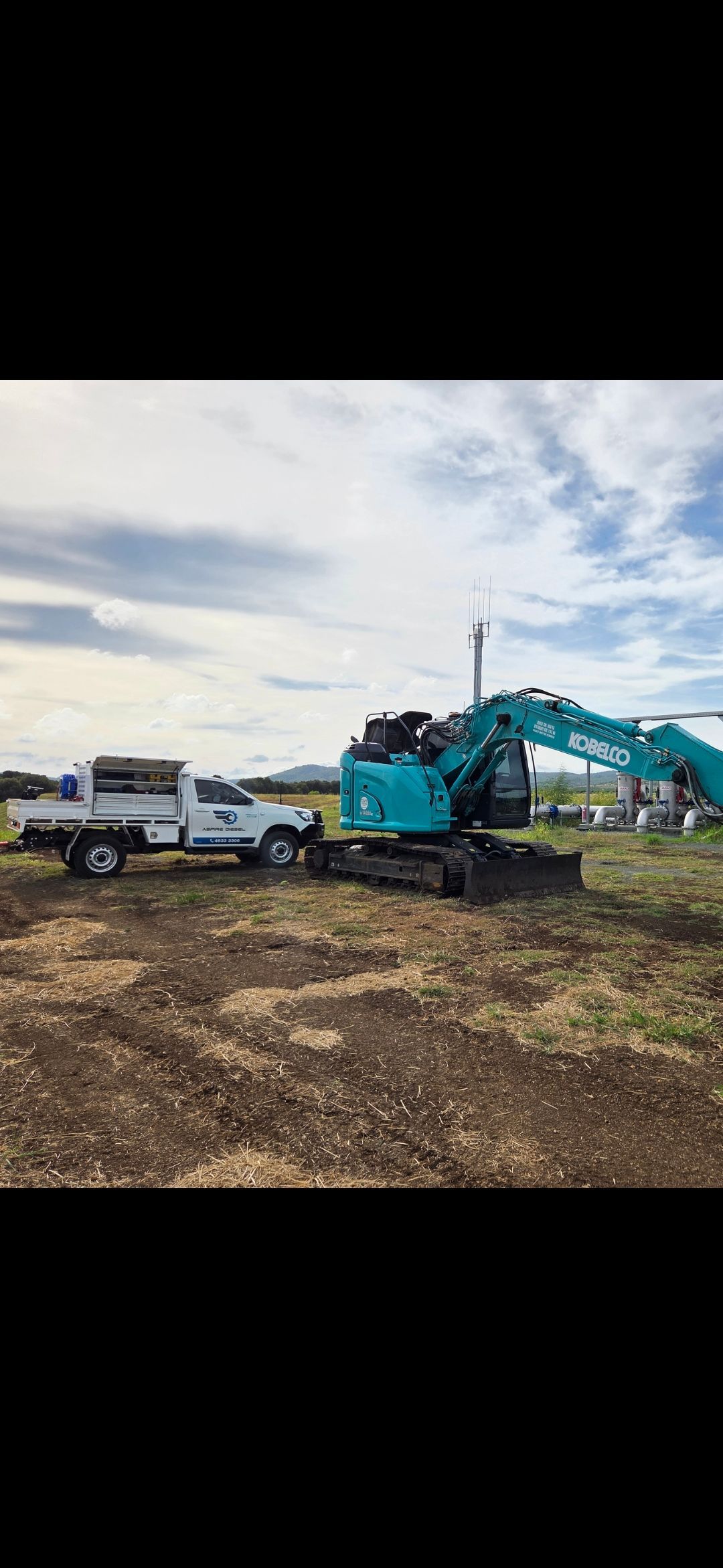 Two work trucks and a turquoise excavator on a dirt lot under a cloudy sky — Aspire Diesel In Gracemere, QLD