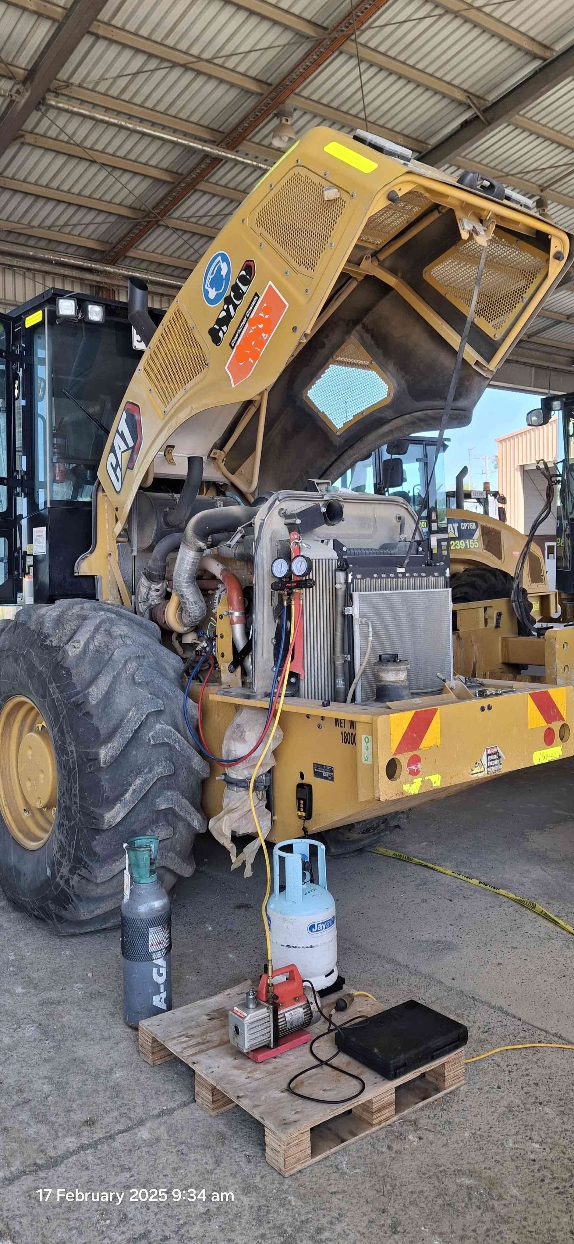 Yellow dump truck with raised hood in a garage, with a person working on the front wheel. — Aspire Diesel In Gracemere, QLD