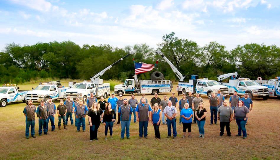 A large group of people standing in front of a row of trucks.