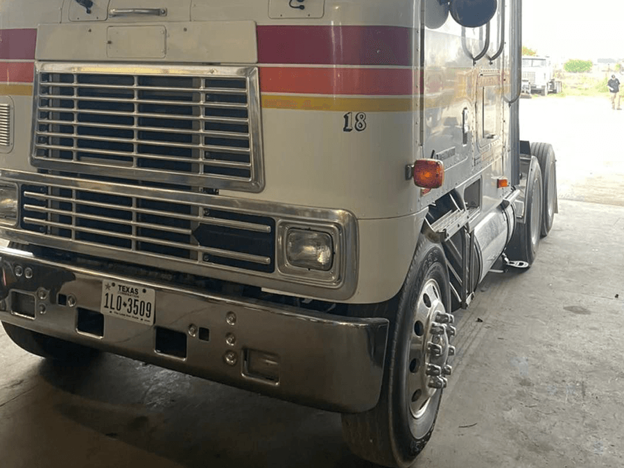 A white truck with red and yellow stripes is parked in a parking lot.