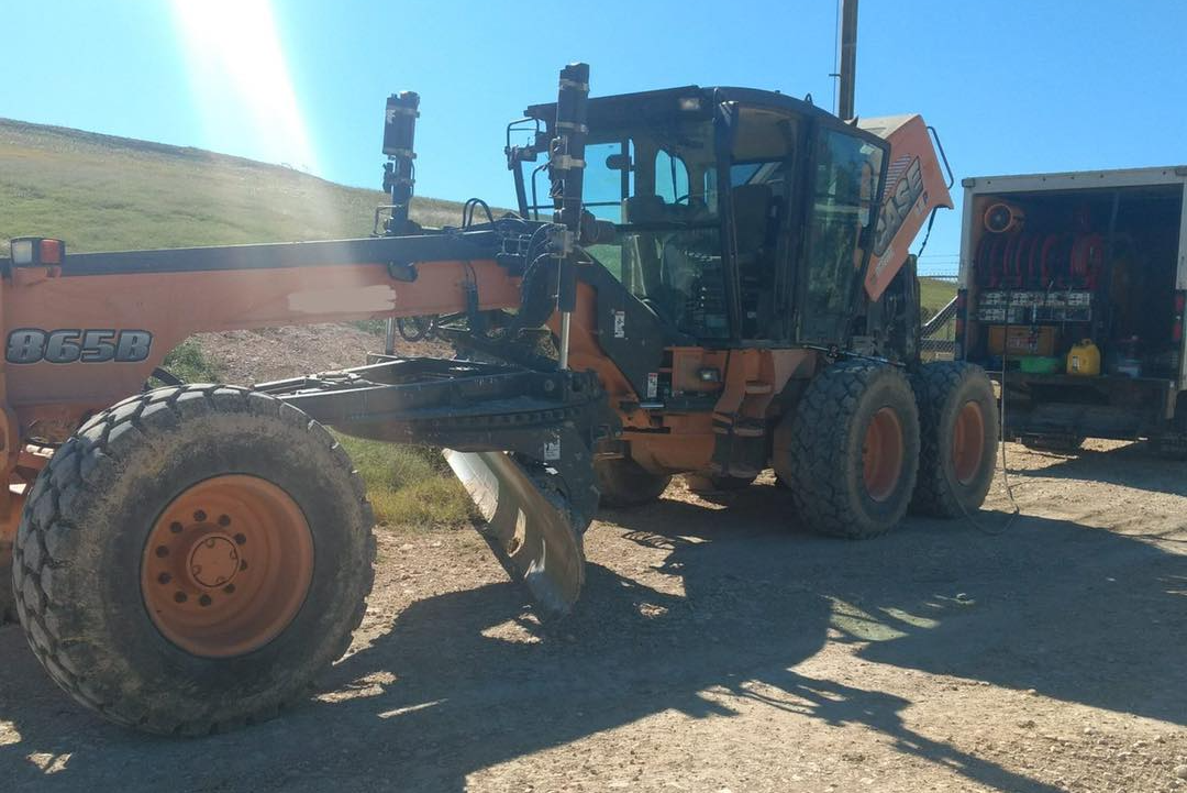 A case tractor is parked on a dirt road next to a truck.