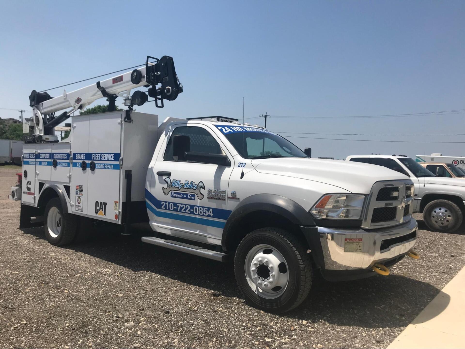 A white truck with a crane on top of it is parked in a parking lot.