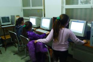 Niños frente a las computadoras en un aula, concentrados en las pantallas.