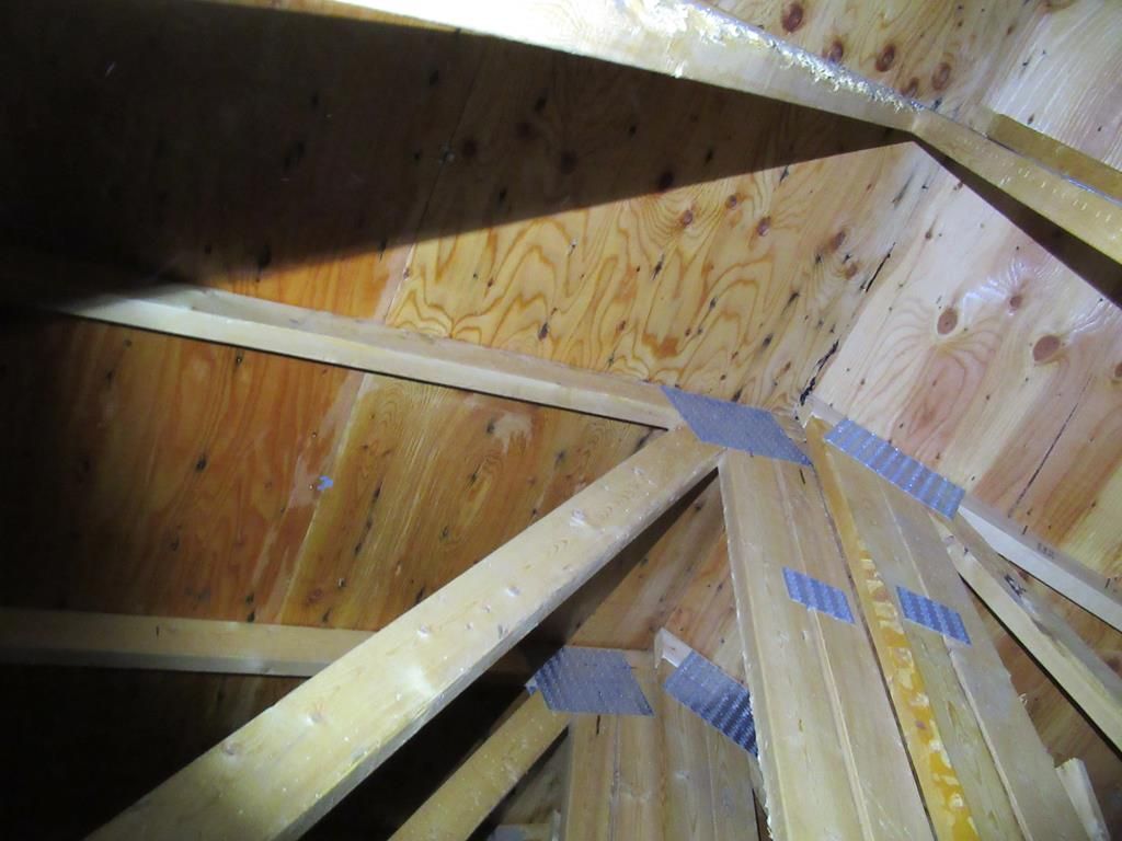 Charpente en bois des combles avec revêtement en contreplaqué, la lumière brille d'en haut.