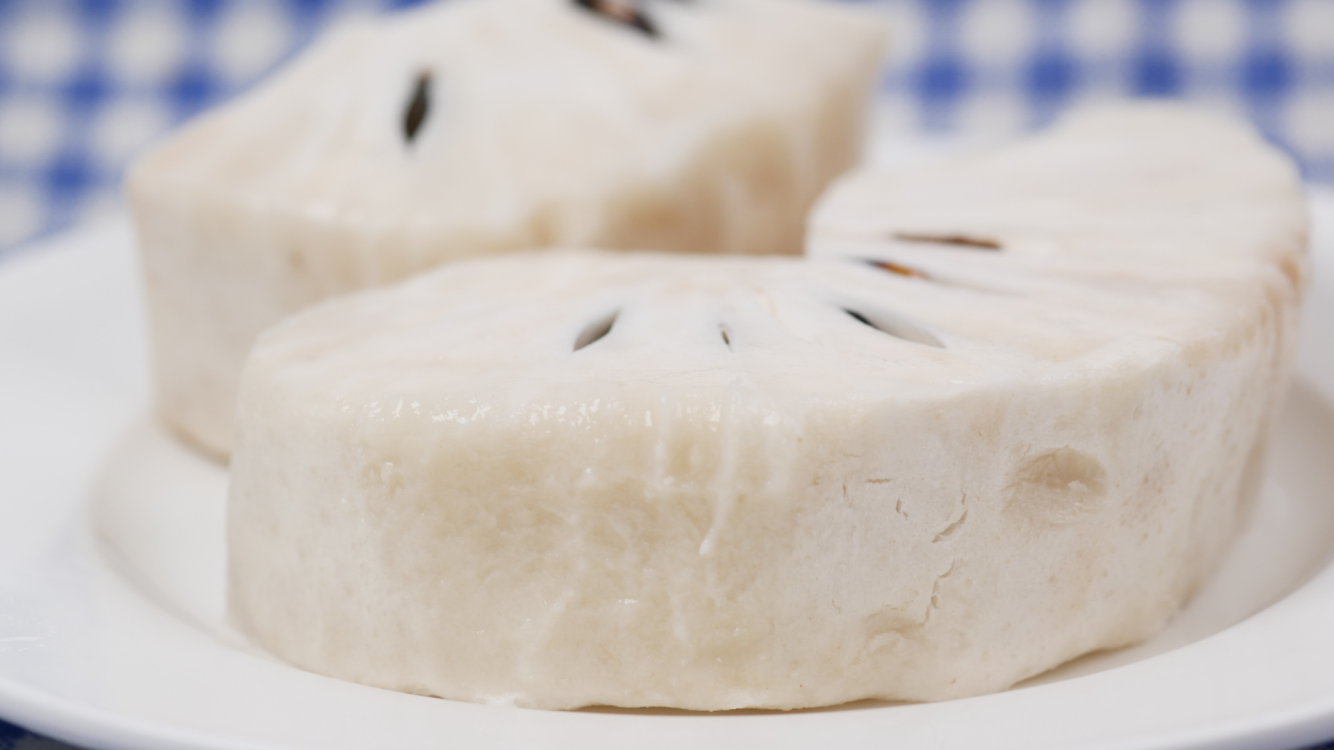 Um prato branco coberto com fatias de comida sobre uma toalha de mesa xadrez.