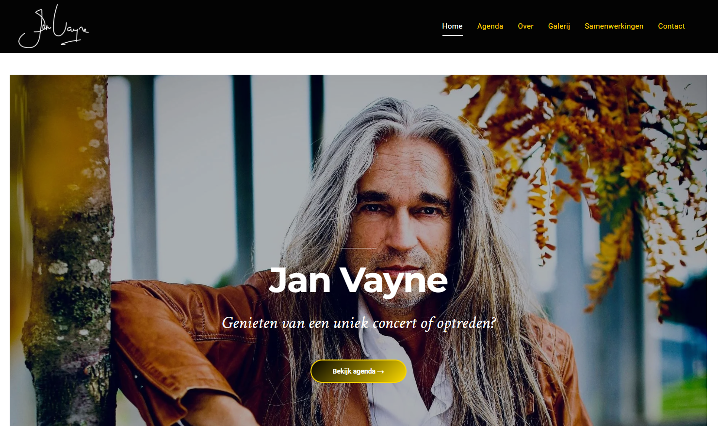 Een man met lang haar zit naast een boom op een website.