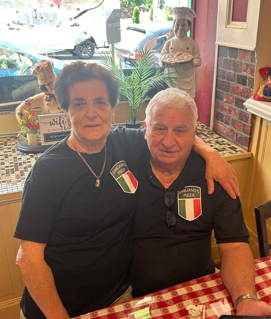 A man and a woman are posing for a picture while sitting at a table.