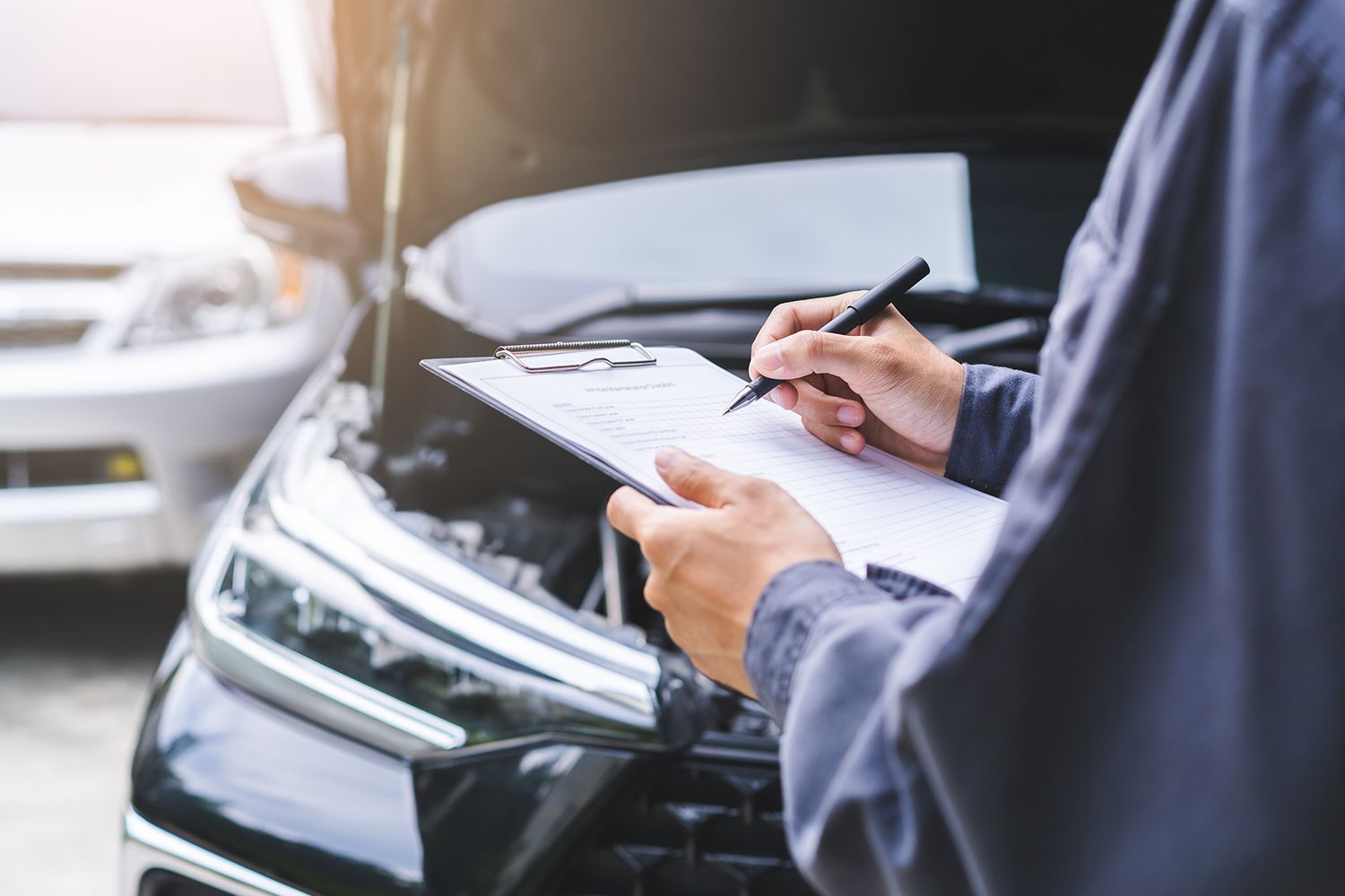 Mechanic with clipboard inspecting car engine. Mechanic with clipboard inspecting car engine.
