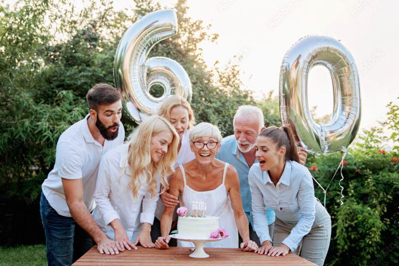 Adult Social Event 60th birthday party with group laughing and holding number shaped balloons