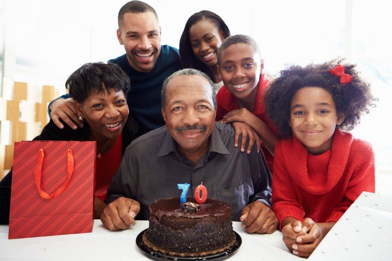 Adult Social Event 70th birthday party with group in front of chocolate cake
