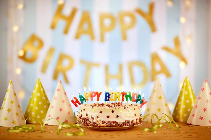 Teen birthday party cake surrounded by cone shaped party hats and ribbons