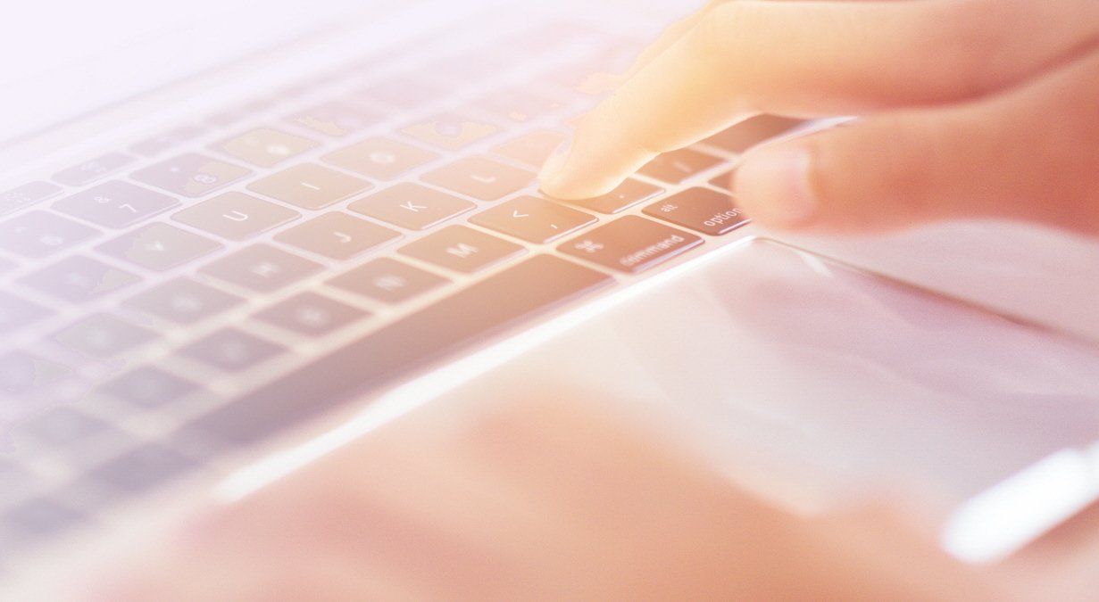 Hands typing on a laptop keyboard; close-up view with bright lighting.