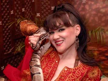 Woman in ornate red outfit holding a large snake, smiling.