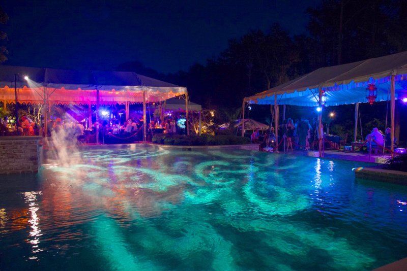 This Event Planning Lighting Checklist provides 9 important questions to ask your lighting vendor plus additional details to consider for outstanding lighting at your event. a large swimming pool is lit up at night with colorful designs