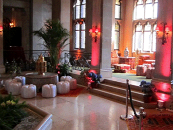Elegant interior with marble floor and columns, seating, and red ambient lighting.
