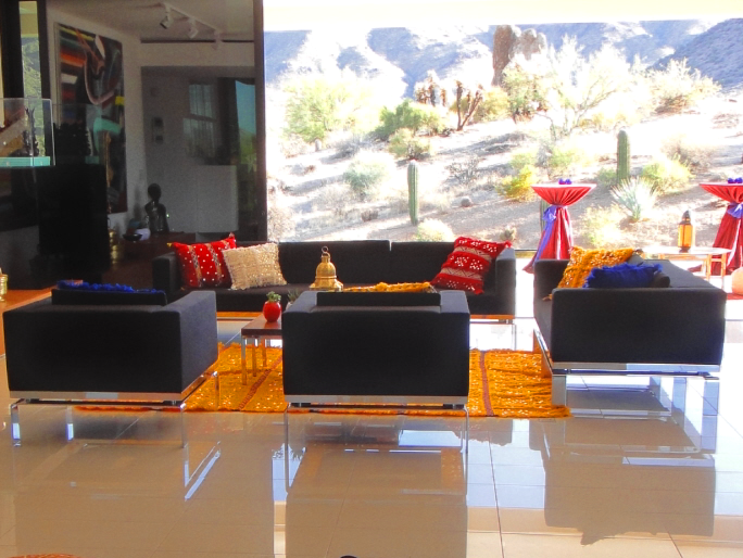 Modern lounge area with black seating, vibrant pillows, and an outdoor desert view.