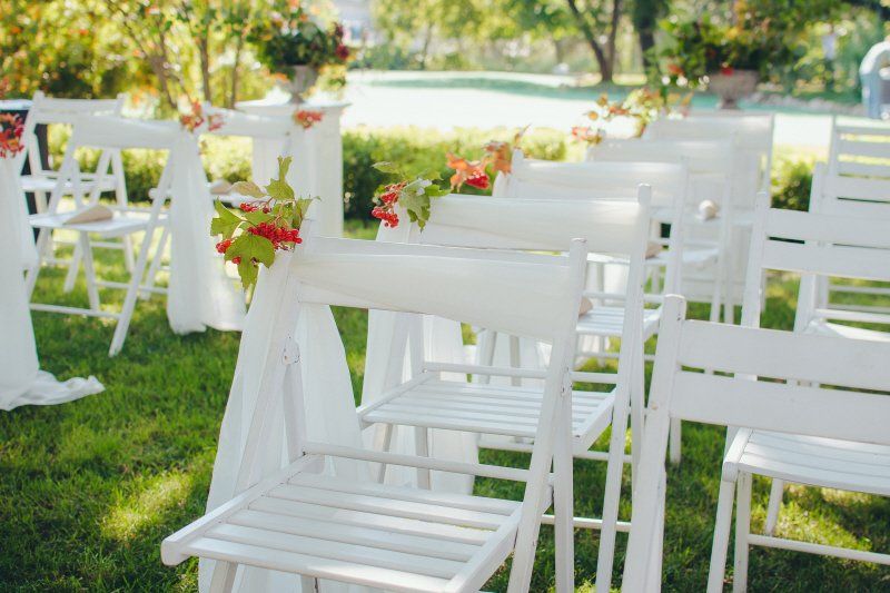 Elevate your party with the party rentals checklist. This party planning checklist discusses questions to ask your party rental supplier. a row of white folding chairs with decorations on the backs