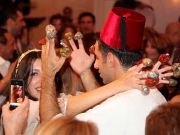 Bride and groom dancing at a wedding, with candy rings on their fingers, and others in background.