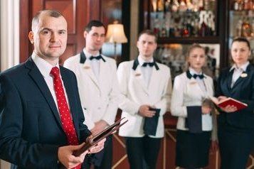 Elevate your event planning with our site inspection checklist and essential questions for venues. Trust Zohar Productions for a flawless venue selection process! a man in a suit and tie is standing in front of a group of waiters and waitresses.