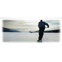 Person playing hockey on a frozen lake with mountains in the background.