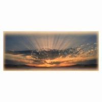 Sunset over mountains with sun rays breaking through clouds.