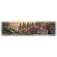Autumn landscape with mountains, trees, and a church bathed in warm light.