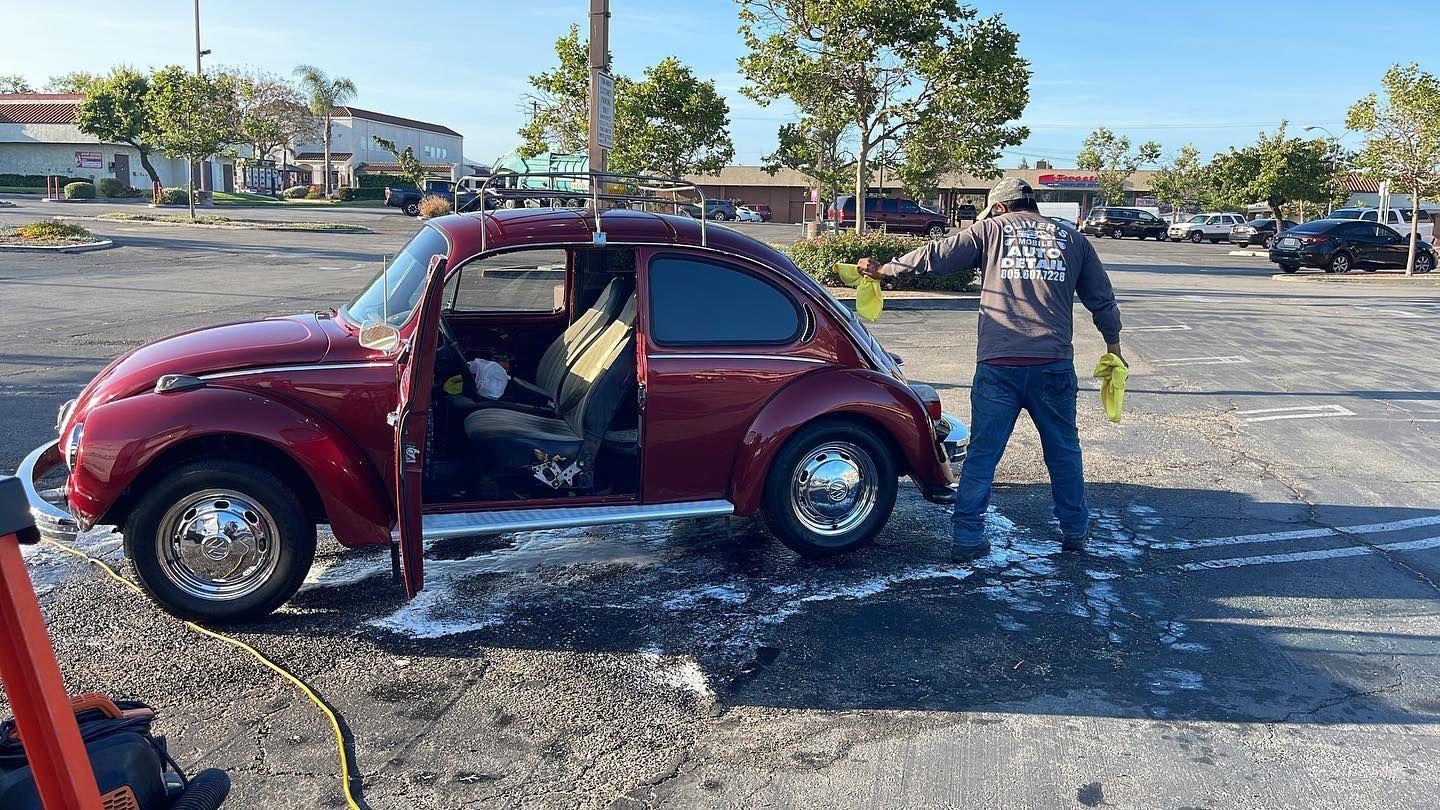 Red compact car with open doors in a flooded parking lot, a person walking beside it.