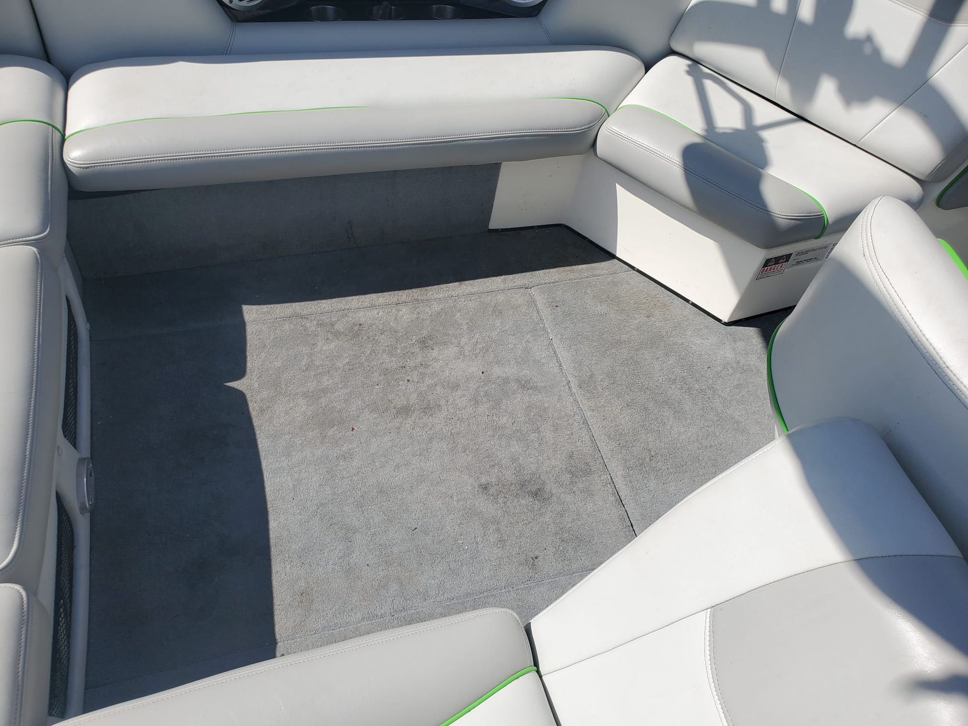 Empty white boat seating area with gray carpeted floor and benches around the edge