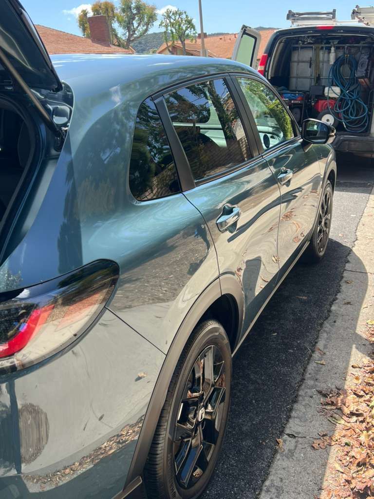 Gray SUV parked on the street with its rear hatch open beside another vehicle