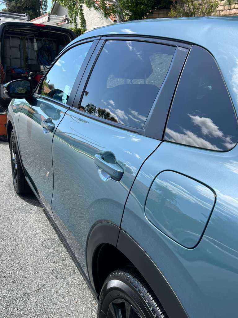 Blue SUV parked outdoors with an open trunk and reflections in the tinted windows.