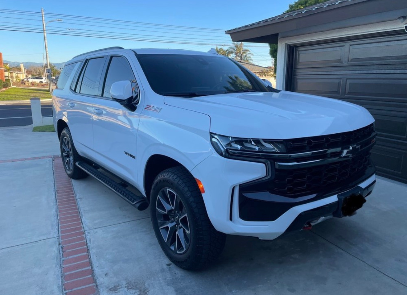 White SUV parked in a driveway beside a garage on a clear day