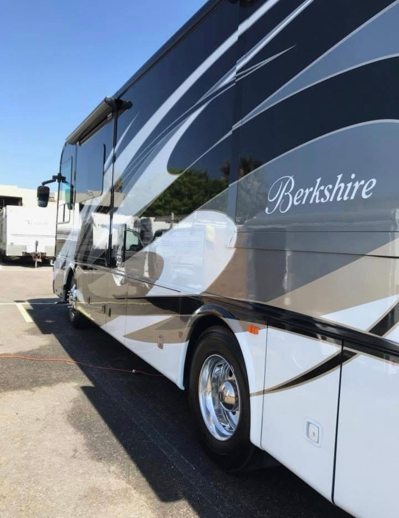 Black and silver Berkshire luxury motor coach parked outdoors under a clear sky