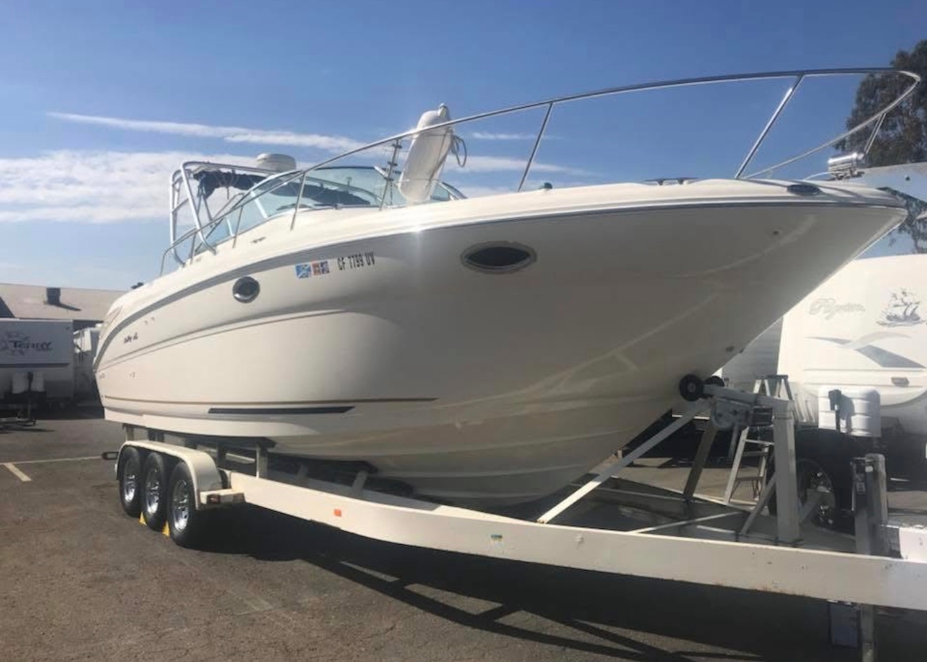 White motor yacht on a trailer in a boat yard under a clear blue sky