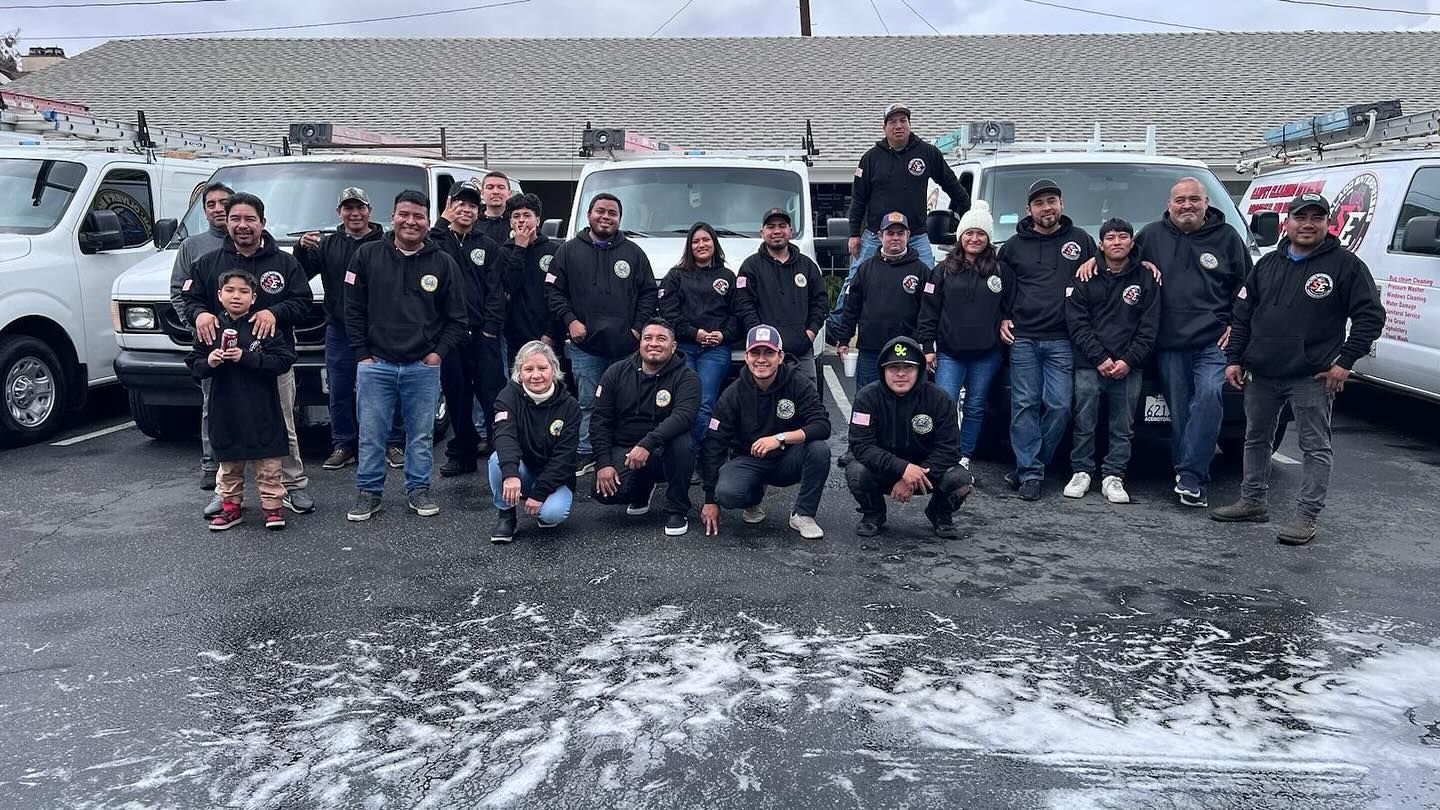 Group of people posing outdoors in snowy weather in front of parked vehicles and bleachers