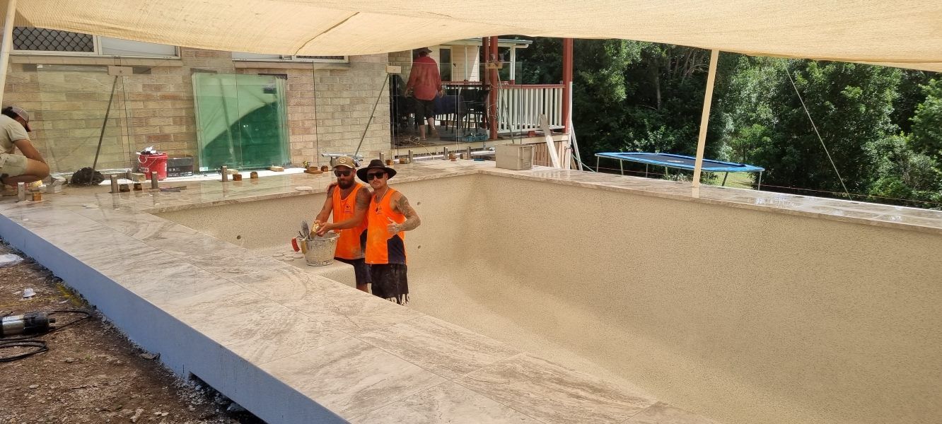 Two Men Are Working On A Swimming Pool Under A Canopy — CJB Pools in Gympie, QLD