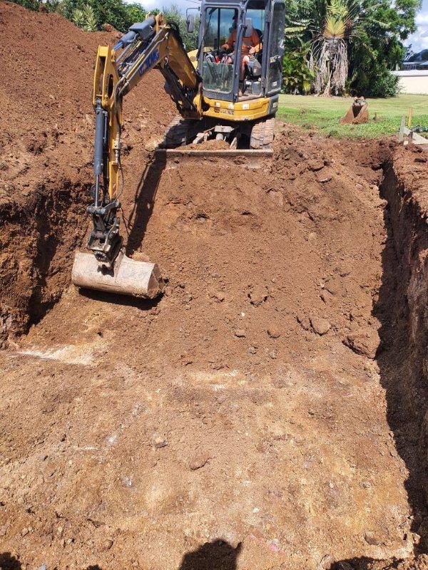 An Excavator Is Digging A Hole In The Ground — CJB Pools in Gympie Southside, QLD