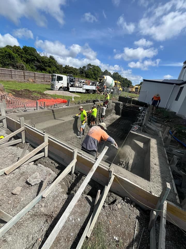 A Group Of Construction Workers Are Working On A Construction Site — CJB Pools in Veteran, QLD