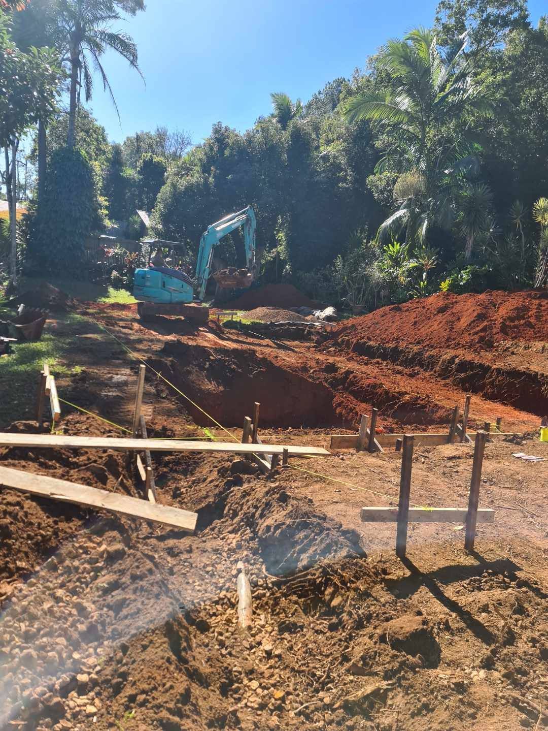 A Yellow Excavator Is Digging A Hole In The Dirt In Front Of A House — CJB Pools in Gympie, QLD