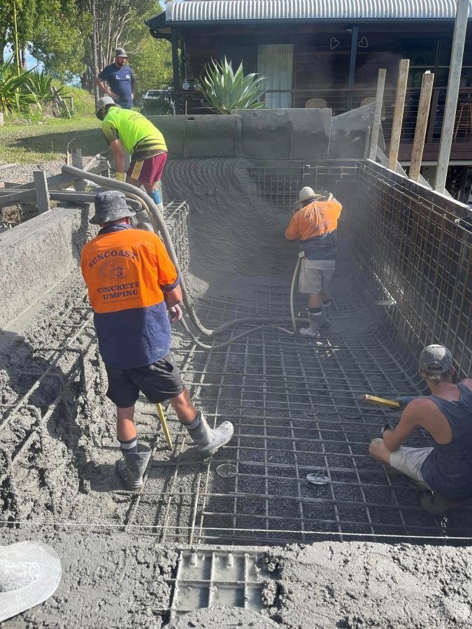 A Group Of Construction Workers Are Working On A Concrete Floor — CJB Pools in Curra, QLD