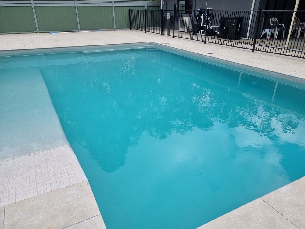 A Large Swimming Pool With A Fence Around It — CJB Pools in Curra, QLD