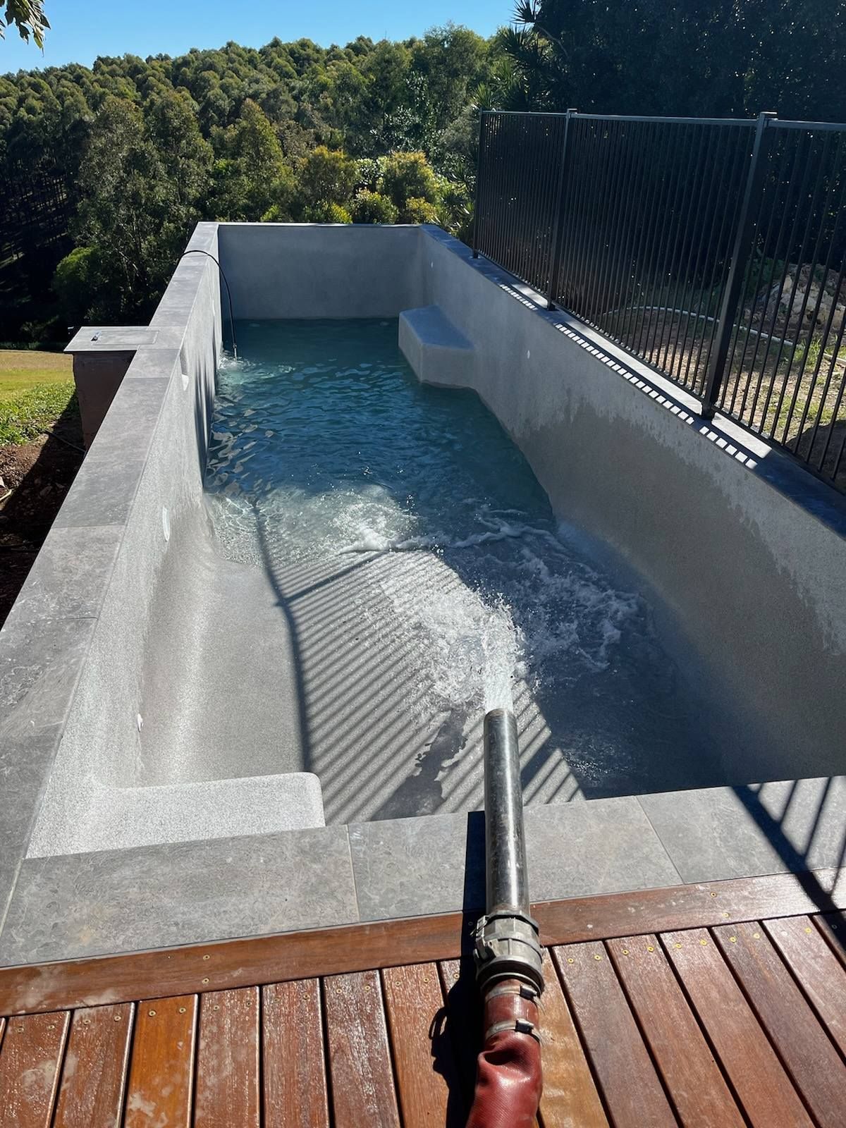 A hose is spraying water into a swimming pool — CJB Pools in Gympie, QLD