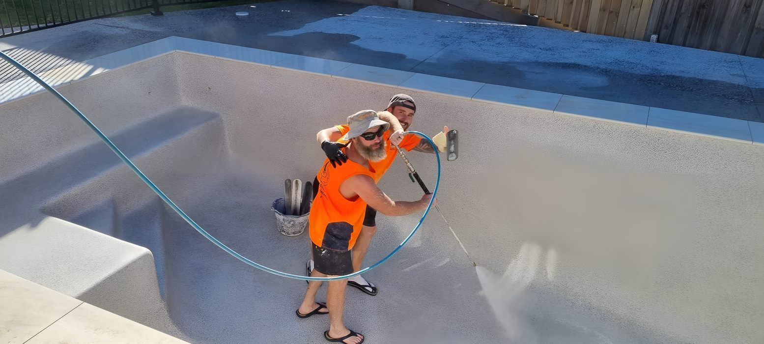 Two People Are Cleaning A Swimming Pool With A Hose — CJB Pools in Curra, QLD