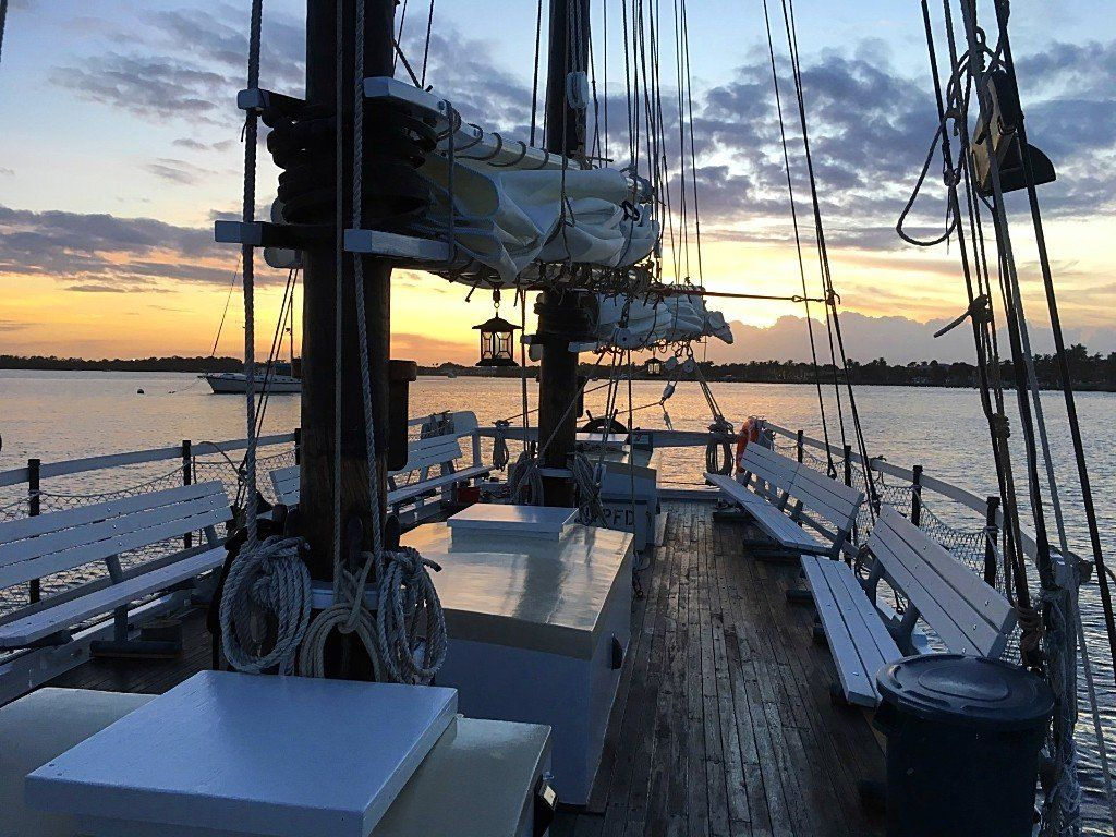 The deck of a sailboat with a sunset in the background.