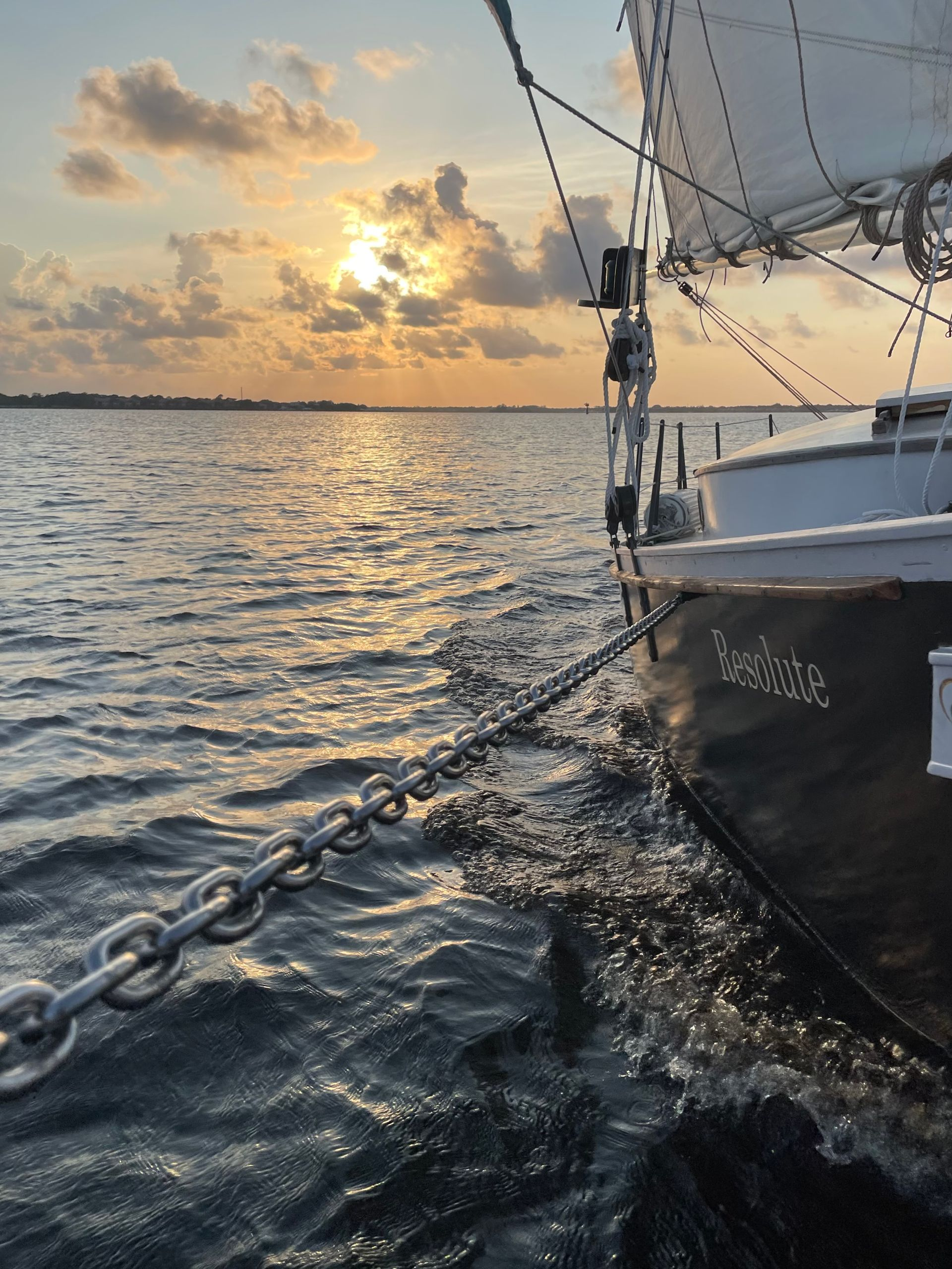 A sailboat is anchored in the water at sunset