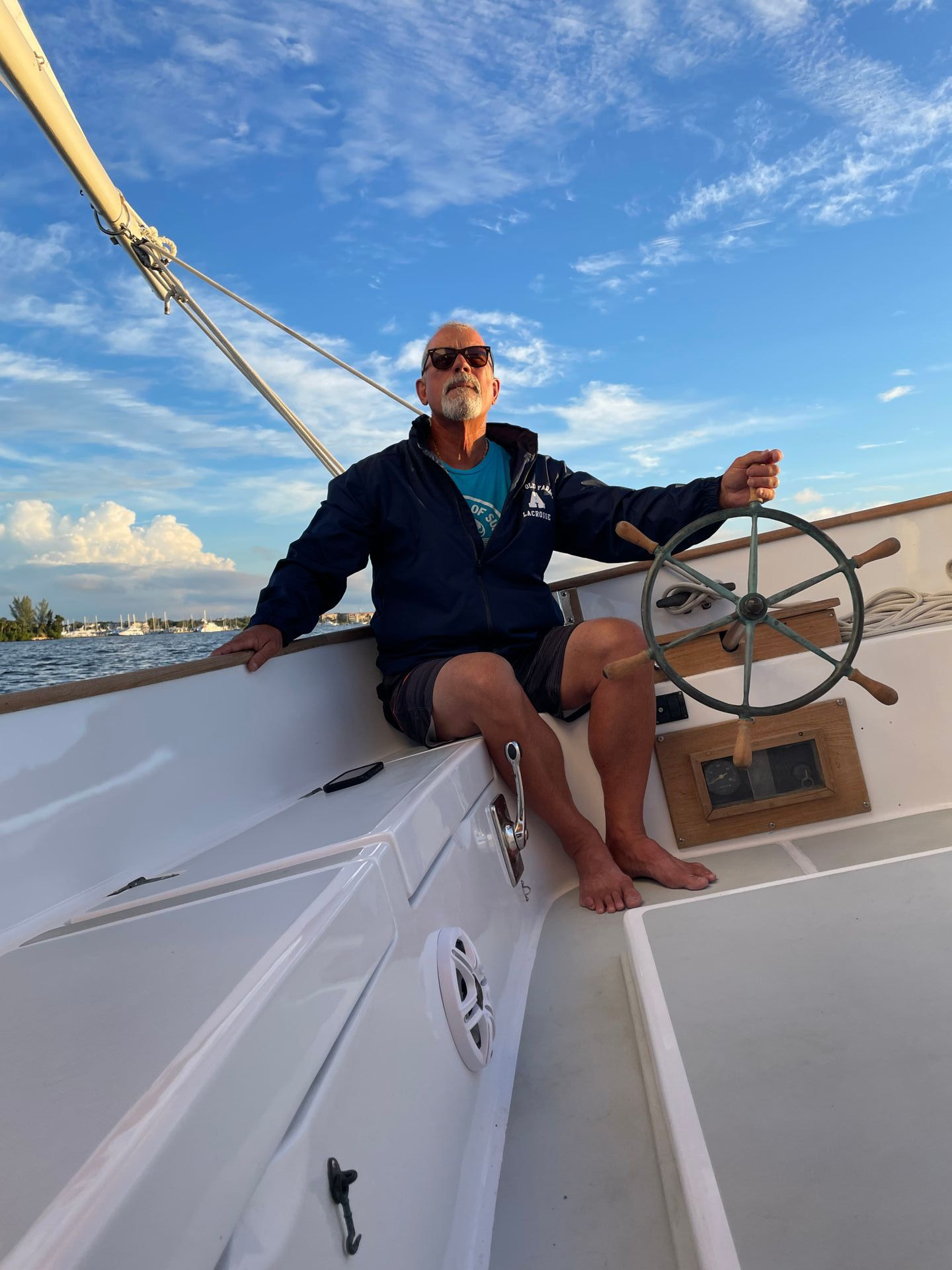 A man is sitting on a boat holding a steering wheel.