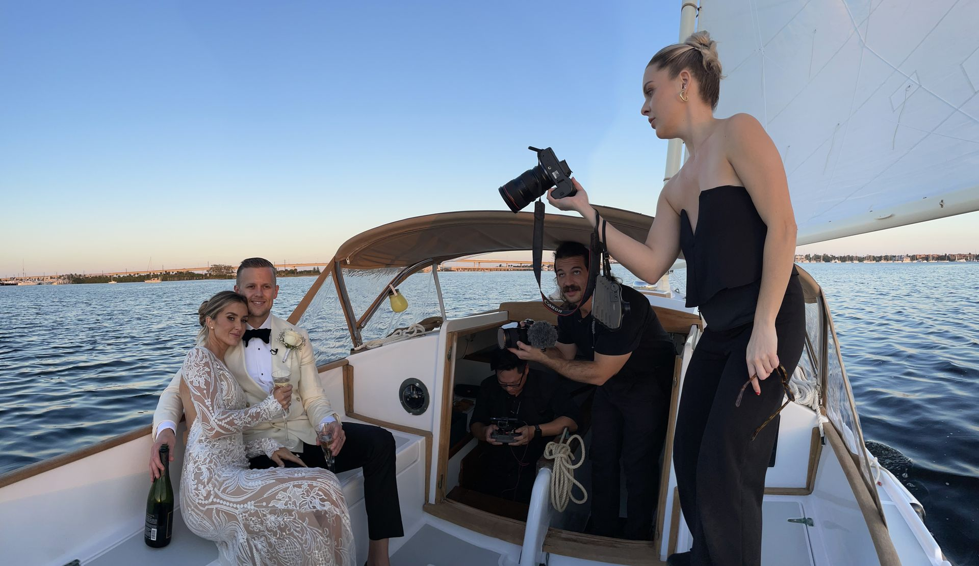A woman is taking a picture of a bride and groom on a boat.