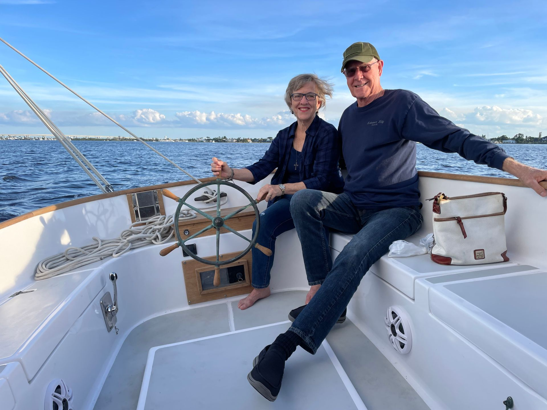 A man and a woman are sitting on the deck of a sailboat.