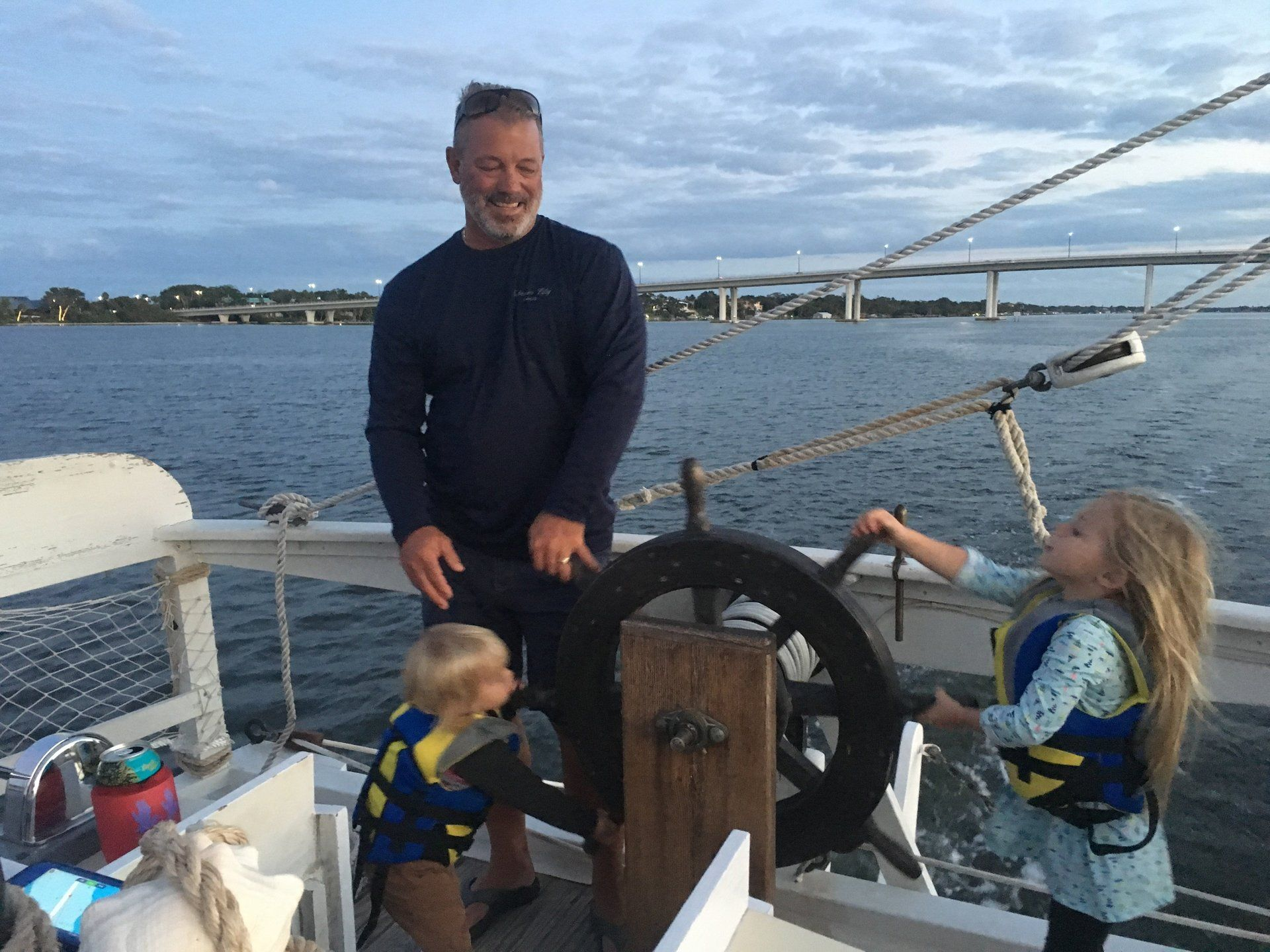 A man and two children are steering a boat in the water.
