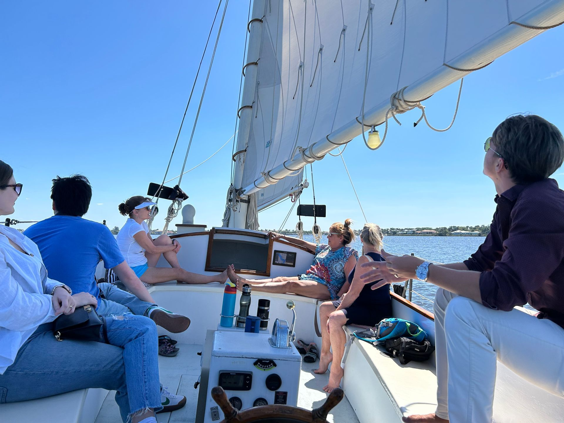 A group of people are sitting on the deck of a sailboat